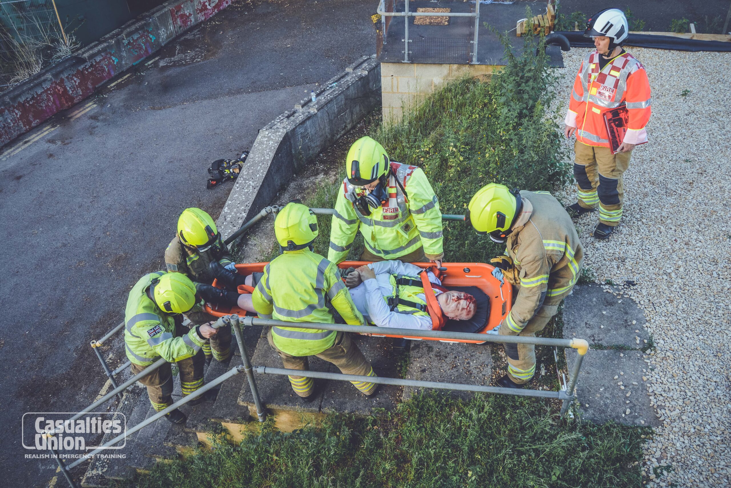 A man being carried on a stretcher down some steps by members of a fire service.